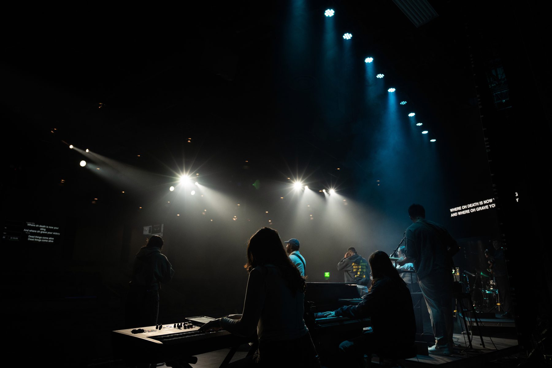 A worship team leading on stage under bright stage lighting